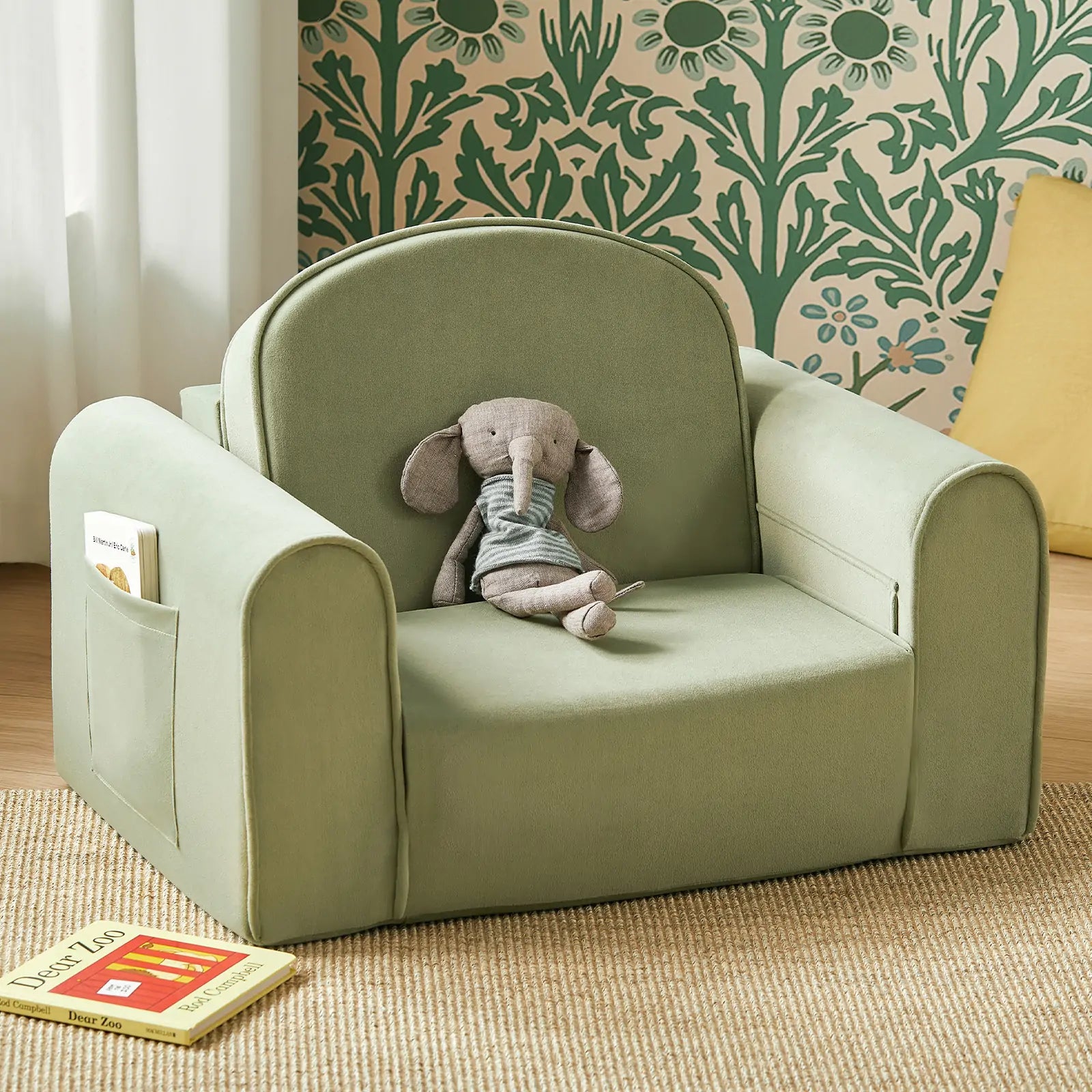 Children's green armchair with a stuffed elephant toy and a book on a beige carpet. Main image