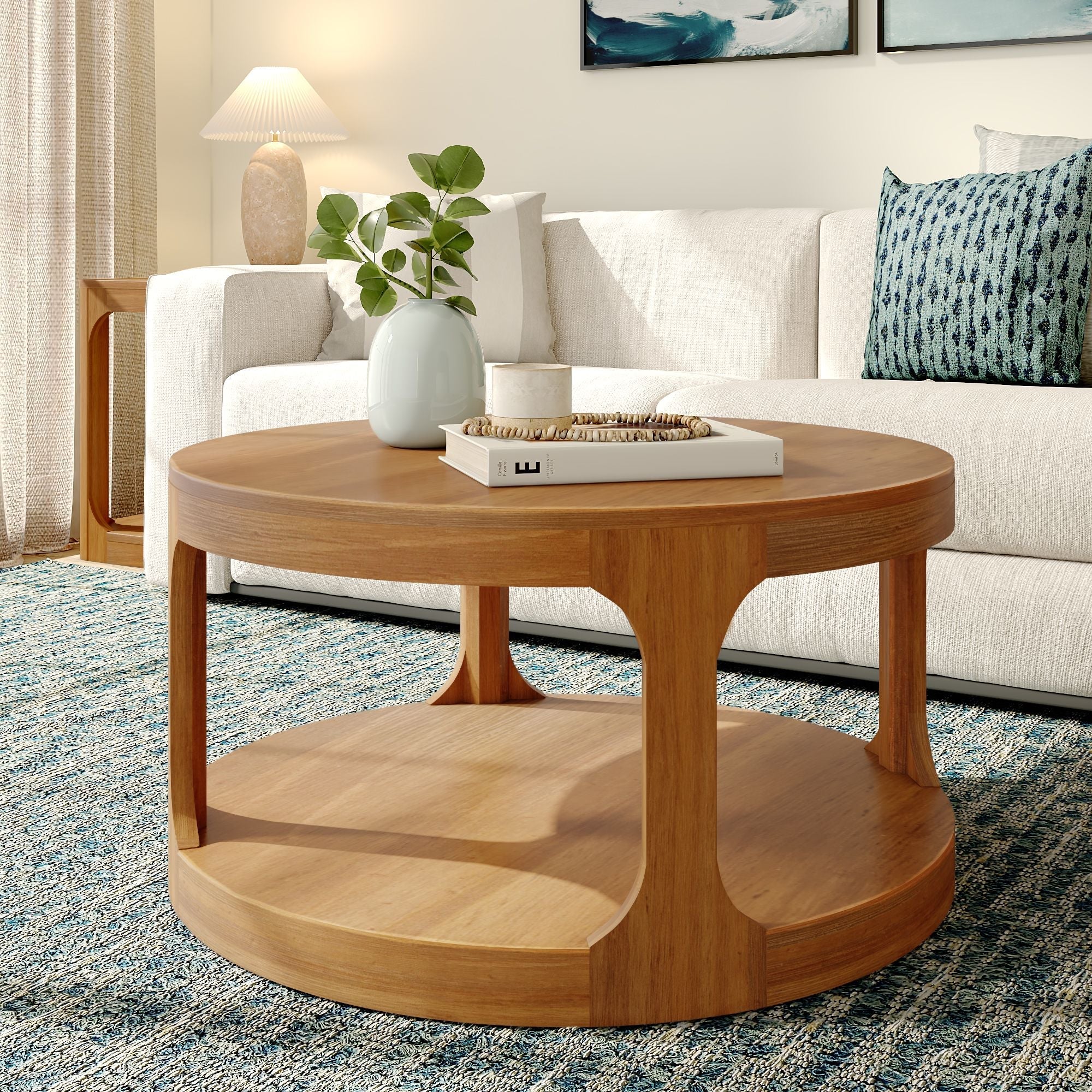 Round mid-century modern wooden coffee table with white vase and book in a bright living room with beige sofa and blue rug Main image