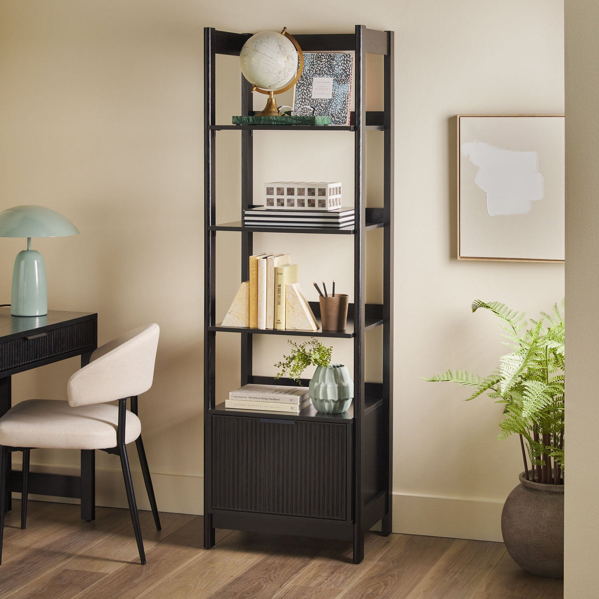 Tall black bookshelf with decorative items in a home office setting.