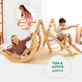 Children playing with wooden climbing toys in a room with a white wall.