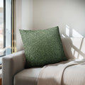 Green textured pillow on a beige sofa with natural light