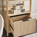 Wooden shelf with an open drawer containing books and decorative items.
