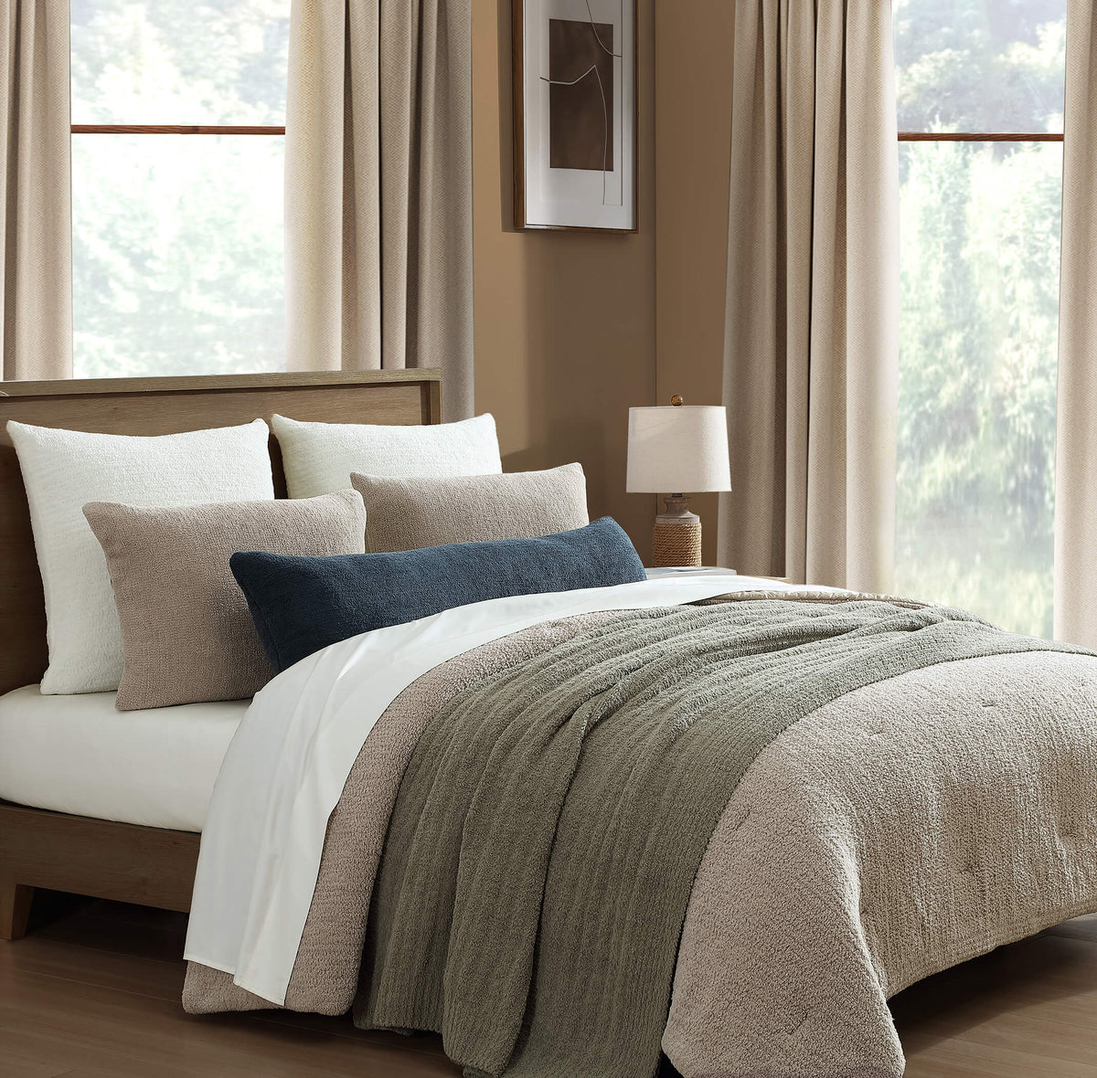 Neatly made bed with pillows and a blanket in a well-lit bedroom.