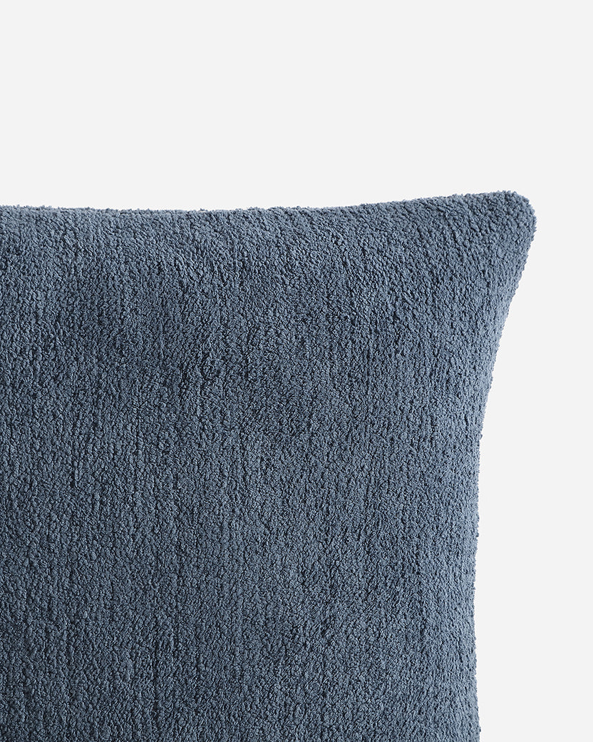 Close-up of a textured blue pillow on a light gray background