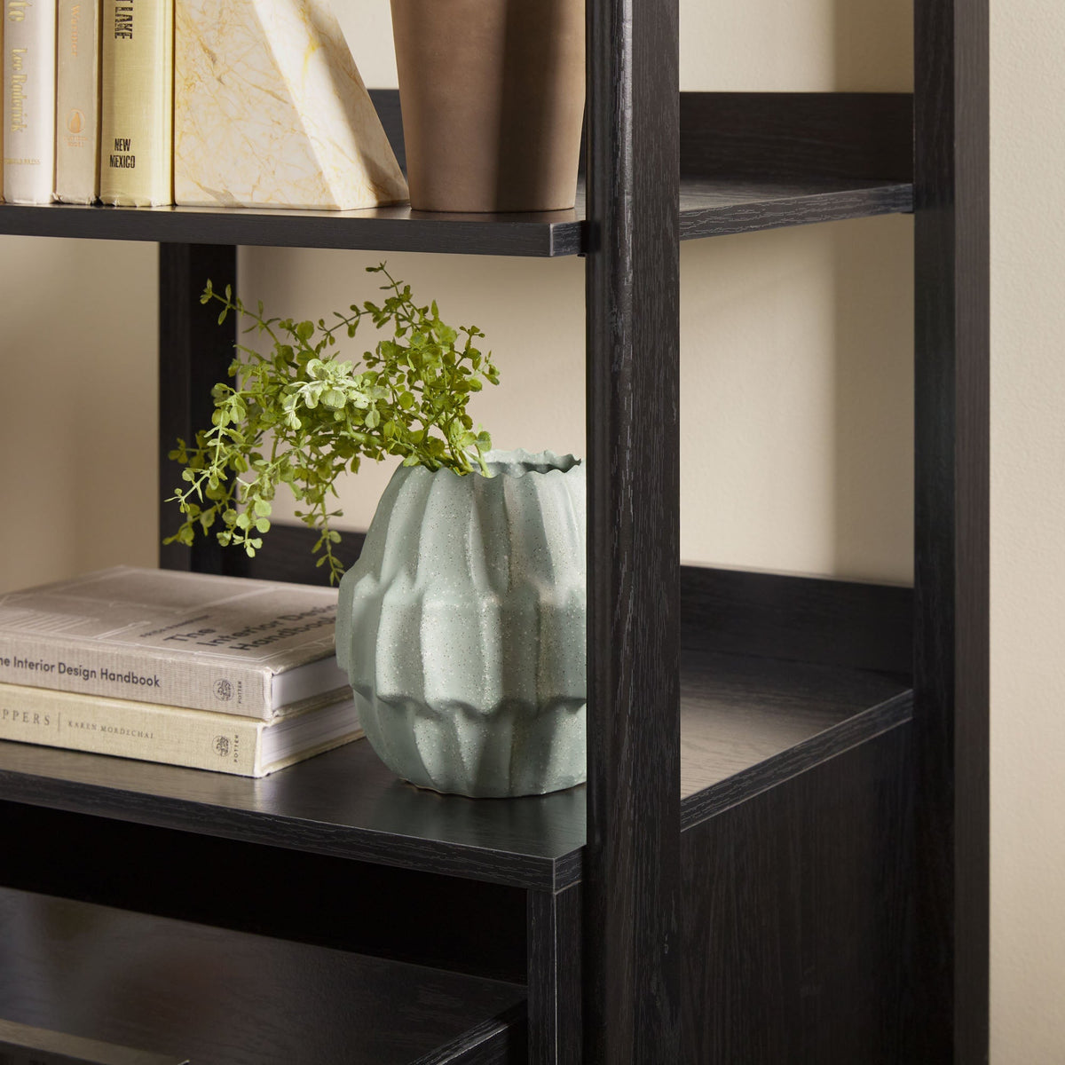 Bookshelf with books and a green vase on a neutral background