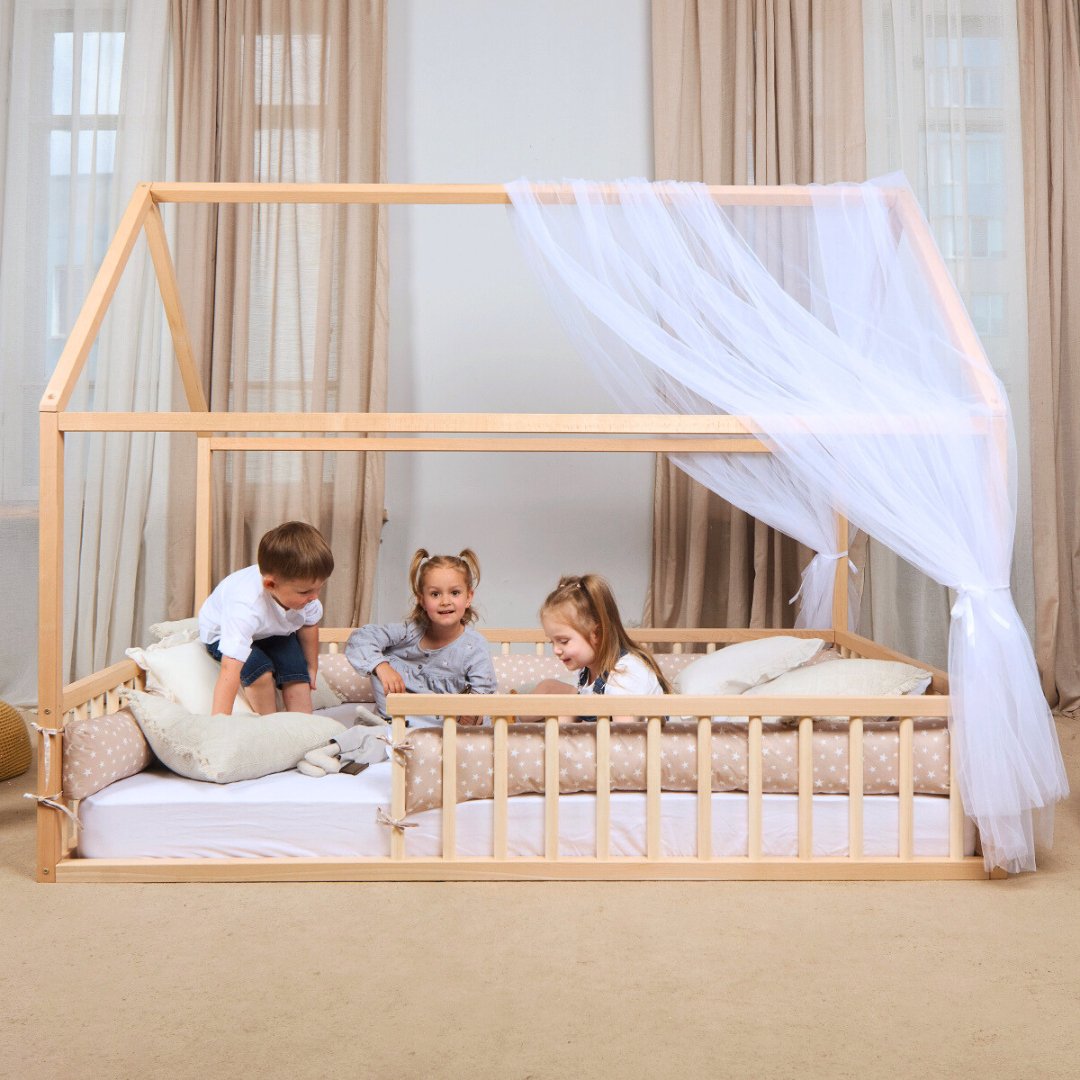 Children playing on a wooden bed with a canopy in a bright room.